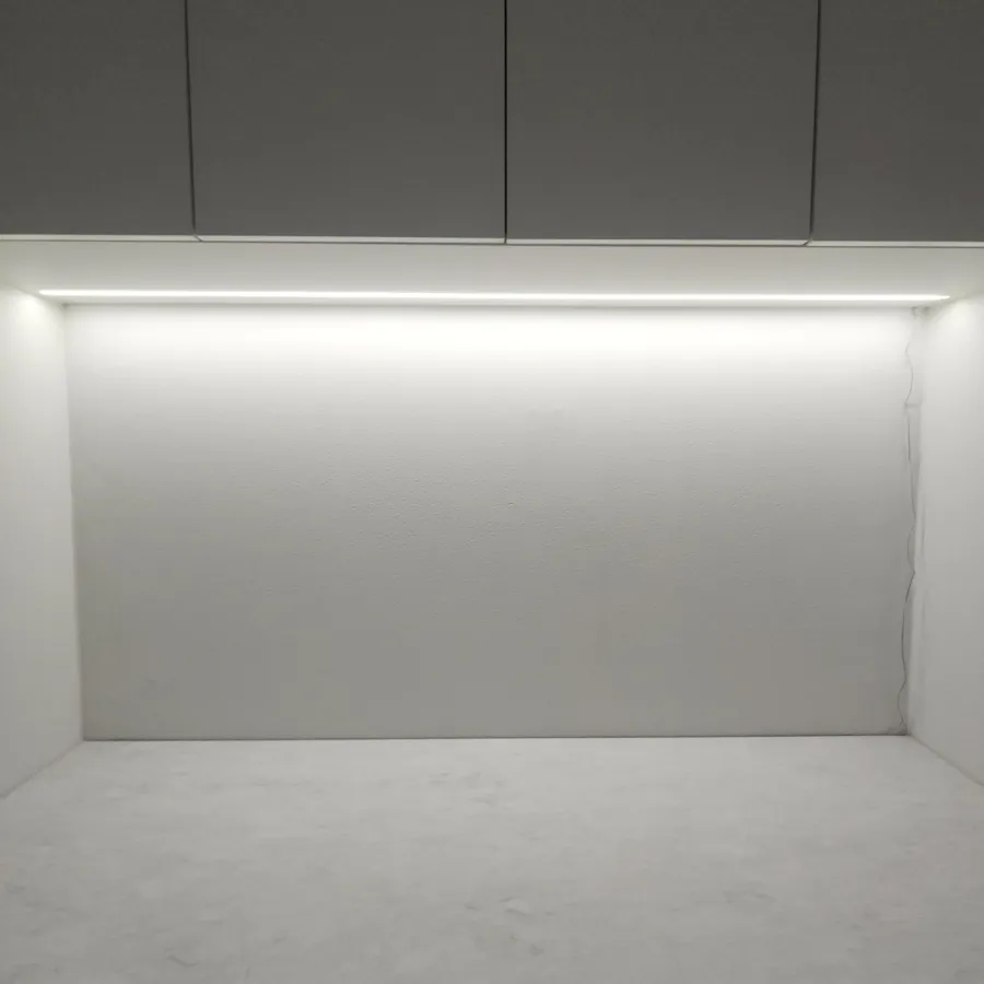 상부장 아래 LED 조명이 켜진 흰 벽면과 하얀 작업대 상판을 점검하는 모습