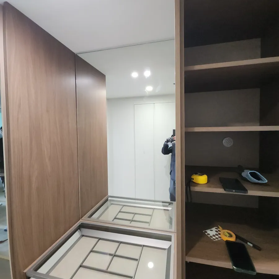 갈색 수납장과 선반 사이에서 거울에 드레스룸 내부가 비치는 모습
