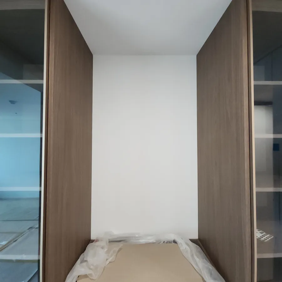 좌측에 유리문 수납장, 우측에 우드 수납장이 있고 가운데 흰 벽이 비어 있는 모습